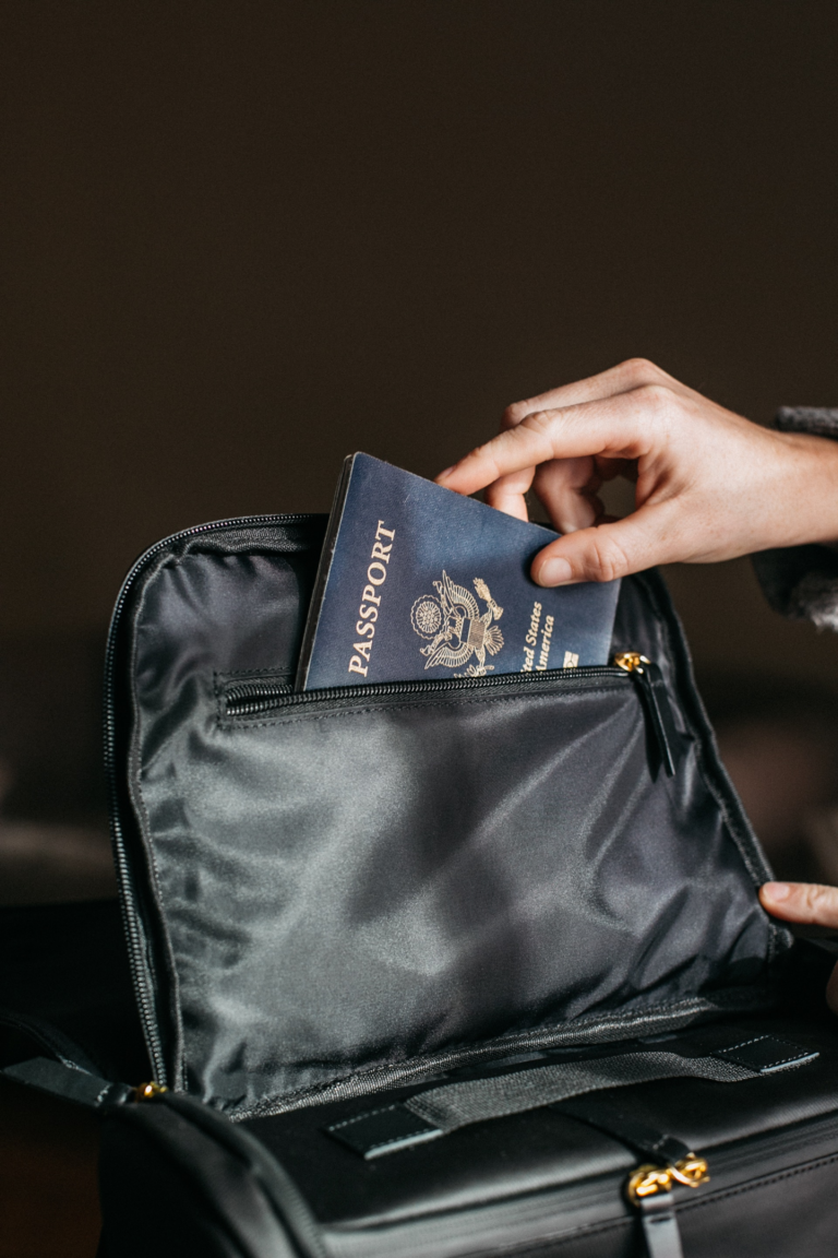 Eine Hand, die einen Reisepass auf eine Tasche legt.