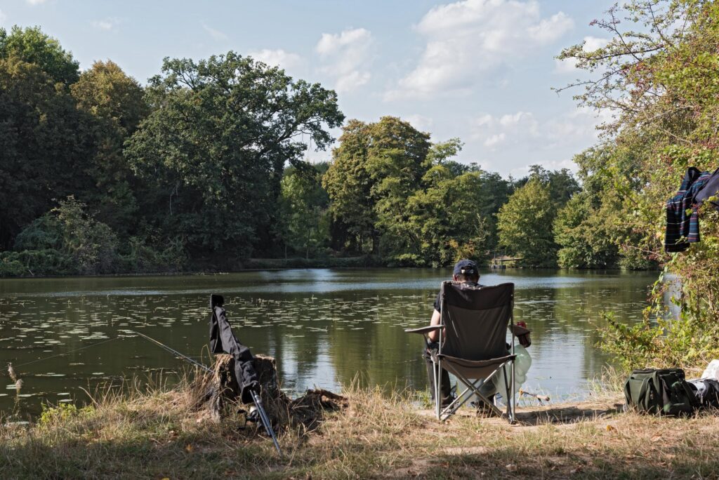 Ein Angler sitzt an einem kleinen Waldsee in Hessen
