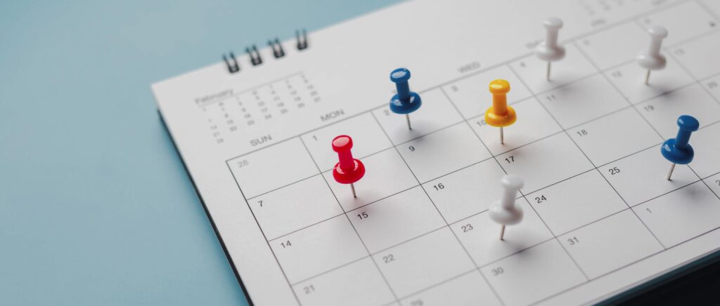 Ein Kalender auf dem mehrere Stecknadeln stecken.