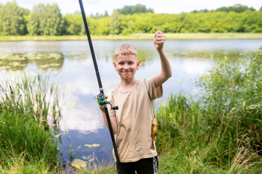 Ein Junger angler pr&auml;sentiert stolz seinen Fang.