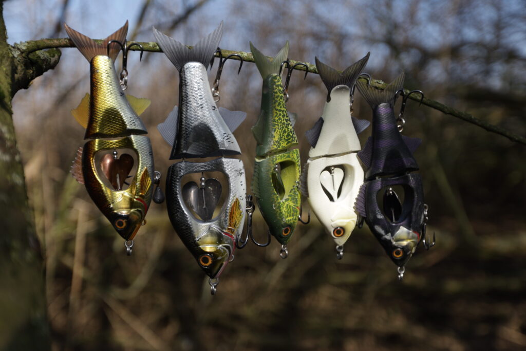 Mehrere Swimbaits h&auml;ngen an den Haken an einem Baum.