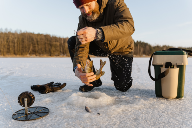 Ein Fischer zieht einen Fisch an der Schnur aus einem Loch im Eis.