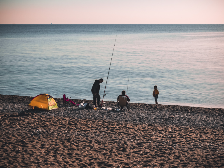 3 Menschen, die am Strand angeln und das Meer genießen.