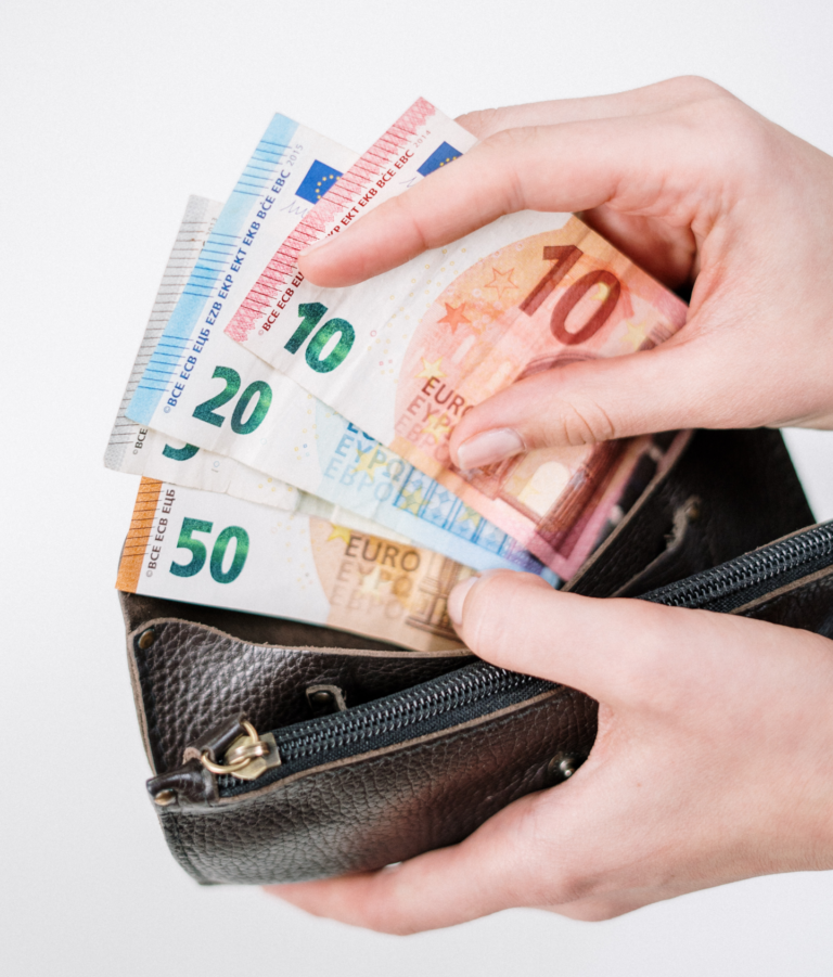 Eine Hand, die aus einer Brieftasche mehrere Euro-Banknoten herauszieht.