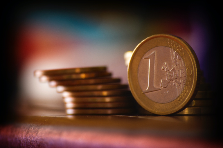 Nahaufnahme einer 1-Euro-Münze neben einem Stapel anderer Münzen.
