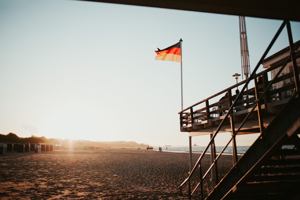 Ein Strand auf Usedom bei klarem Himmel und einer Deutschland-Flagge im Vordergrund.